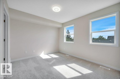 Neutral-toned room featuring light gray carpeting, a flush-mount ceiling light fixture, and white trim - 14 4367 Veterans Way, Edmonton, AB 