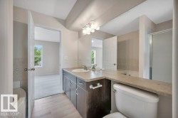 Bathroom featuring a dual vanity with undermount sinks, light-toned countertop, and wood-finish cabinetry - 