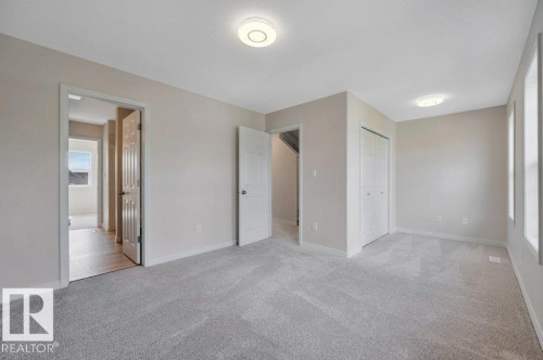 Spacious room featuring light gray carpeting, neutral-toned walls, and recessed lighting - 14 4367 Veterans Way, Edmonton, AB 