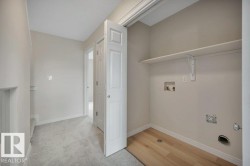 Utility closet featuring wood-finish flooring, a built-in shelf, and appliance hookups - 