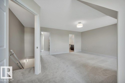 Expansive carpeted room featuring neutral wall tones and a flush-mount ceiling light fixture - 14 4367 Veterans Way, Edmonton, AB 