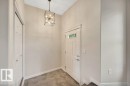 Entryway featuring a decorative pendant light fixture, paneled door with transom windows, and tiled flooring - 14 4367 Veterans Way, Edmonton, AB 