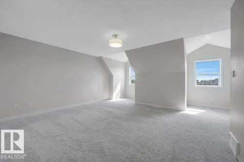 Spacious room featuring vaulted ceilings, light gray wall paint, and gray carpet flooring - 14 4367 Veterans Way, Edmonton, AB 