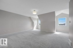 Spacious room featuring vaulted ceilings, light gray wall paint, and gray carpet flooring - 