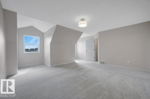 Spacious room featuring light gray carpeting and neutral wall tones - 14 4367 Veterans Way, Edmonton, AB 