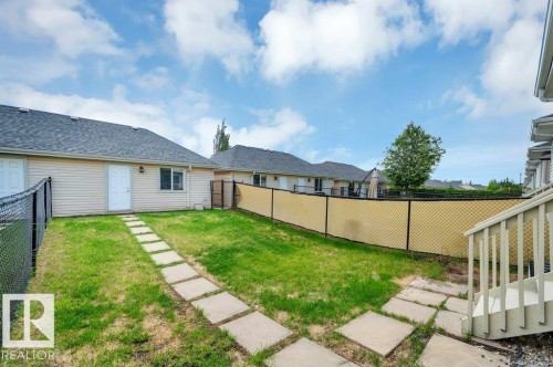 Fenced backyard featuring a manicured lawn and stepping stone pathway - 14 4367 Veterans Way, Edmonton, AB 