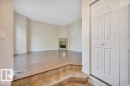 Spacious living area featuring wood-finish flooring, a tiled fireplace with mantel, and ample natural light - 14 4367 Veterans Way, Edmonton, AB 