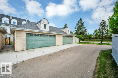 Attached garage with dual overhead doors featuring transom window accents - 14 4367 Veterans Way, Edmonton, AB 