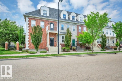 Brick and siding townhome featuring a dormer roofline and individual porch entries - 14 4367 Veterans Way, Edmonton, AB 