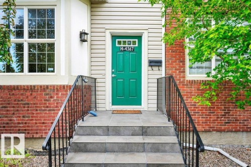 Brick and siding exterior with a vibrant green entry door - 14 4367 Veterans Way, Edmonton, AB 