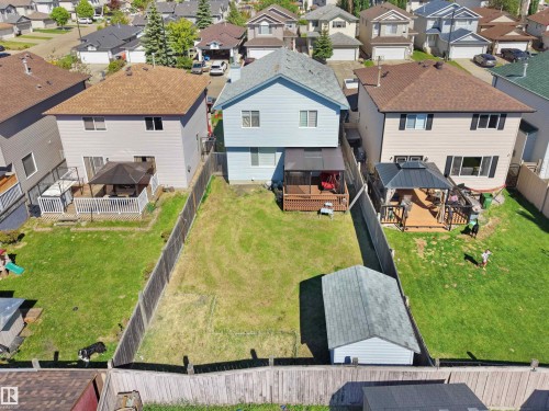 Expansive backyard featuring a manicured lawn, wood fencing, and a detached shed - 2418 32B Street, Edmonton, AB 