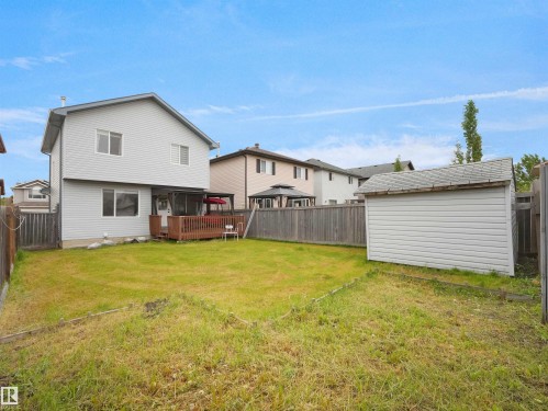 Rear exterior featuring a wood-decked patio, light gray siding, and a detached storage shed - 2418 32B Street, Edmonton, AB 