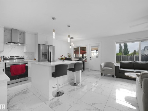 Open-concept living space featuring a gourmet kitchen with stainless steel appliances, white cabinetry, and an eat-at island - 2418 32B Street, Edmonton, AB 