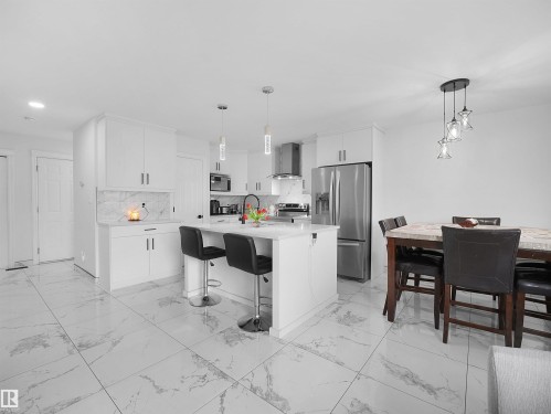 Bright kitchen featuring a central island with white cabinetry and pendant lighting - 2418 32B Street, Edmonton, AB 
