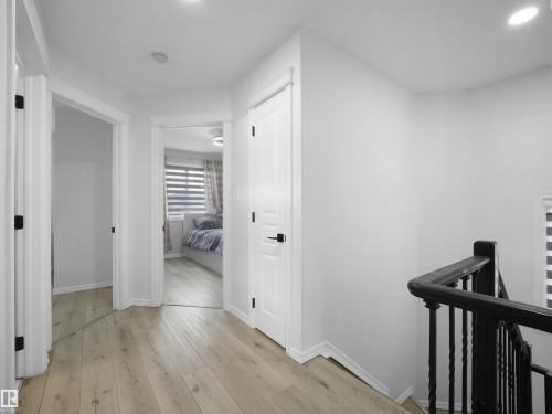 Hallway featuring light wood-finish flooring, white walls, and white trim - 2418 32B Street, Edmonton, AB 
