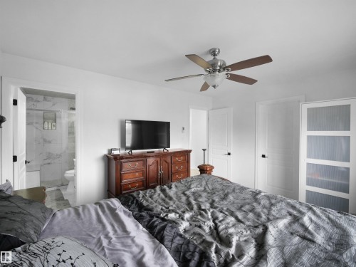 Bright bedroom with white walls and a ceiling fan featuring wood-finish blades - 2418 32B Street, Edmonton, AB 