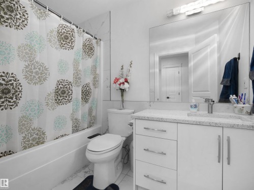 Full bathroom featuring a white tub, white tile surround, and a vanity with a white countertop - 2418 32B Street, Edmonton, AB 
