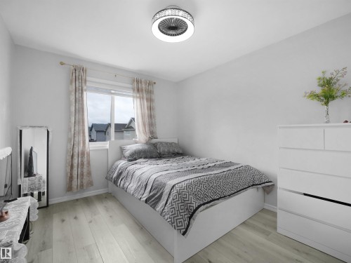 Bright interior space featuring light wood-finish flooring and a contemporary ceiling fan with integrated lighting - 2418 32B Street, Edmonton, AB 