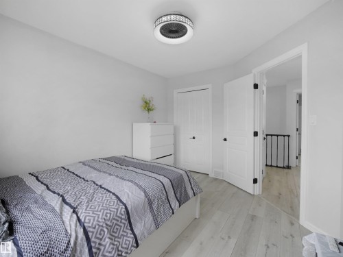 Neutral wall paint, wood-finish flooring, white paneled doors with black hardware, and a modern ceiling light fixture - 2418 32B Street, Edmonton, AB 