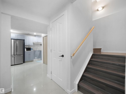Staircase featuring wood-finish treads and a light wood handrail - 2418 32B Street, Edmonton, AB 