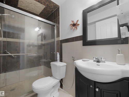 Contemporary bathroom featuring a glass-enclosed shower with tile surround, a wall-mounted shower head, and a chrome grab bar - 2418 32B Street, Edmonton, AB 