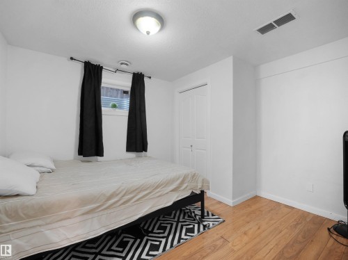 Room featuring wood-finish flooring, white walls, and a window with black curtains - 2418 32B Street, Edmonton, AB 