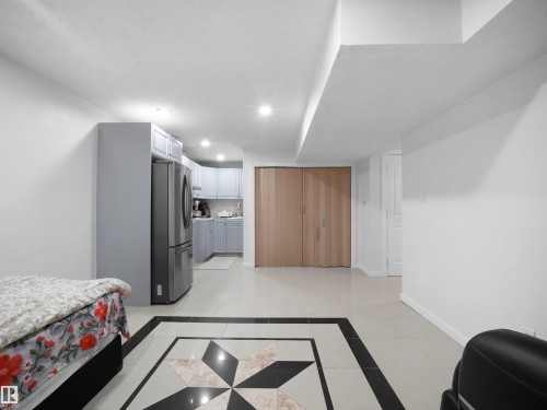 Spacious room featuring light-toned tile flooring with a decorative inlay and recessed lighting - 2418 32B Street, Edmonton, AB 