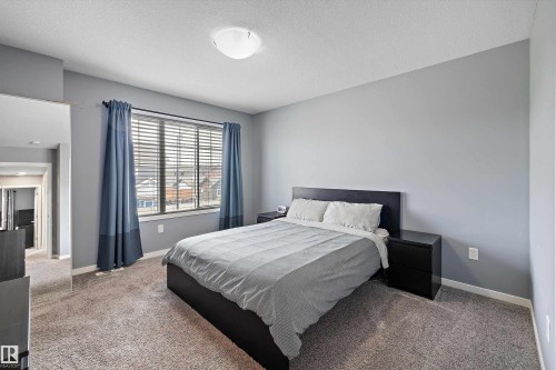 Carpeted bedroom with a window featuring horizontal blinds, flanked by drapes, and a flush-mount ceiling light fixture - 2833 Chokecherry Place, Edmonton, AB 