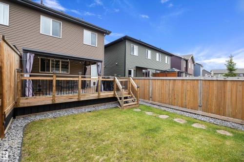 Backyard featuring a wooden deck with black railings, stairs, and privacy curtains - 2833 Chokecherry Place, Edmonton, AB 