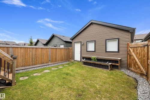 Backyard with green lawn, wooden fencing, and a detached structure featuring horizontal siding - 2833 Chokecherry Place, Edmonton, AB 