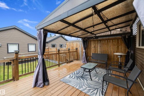Expansive wood deck with a covered pergola featuring overhead string lighting - 2833 Chokecherry Place, Edmonton, AB 