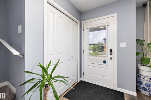 Entryway featuring a paneled door with integrated window, bi-fold closet doors, and wood-finish flooring - 2833 Chokecherry Place, Edmonton, AB 