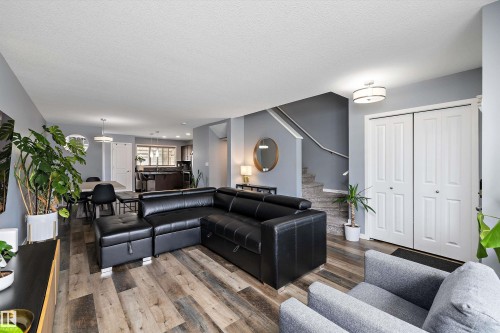 Spacious living area featuring wood-finish flooring, light gray walls, and white bi-fold doors - 2833 Chokecherry Place, Edmonton, AB 