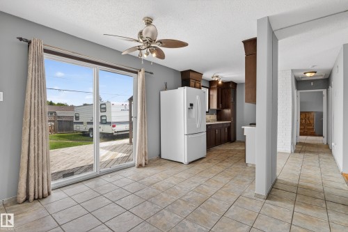 Open-concept living space featuring tile flooring, a ceiling fan, and sliding glass doors leading to a wood-finish deck - 13427 114 Street, Edmonton, AB 