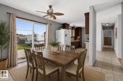 Open-concept dining area featuring a ceiling fan with integrated lighting, direct access to the backyard via sliding glass doors, and durable tile flooring throughout - 
