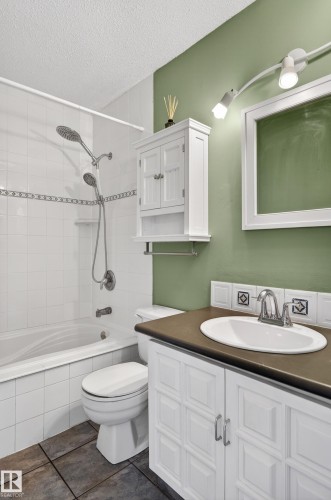 Bathroom featuring a white vanity with paneling, an oval sink, and a dark countertop - 13427 114 Street, Edmonton, AB 
