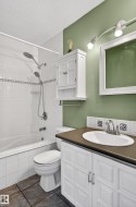 Bathroom featuring a white vanity with paneling, an oval sink, and a dark countertop - 