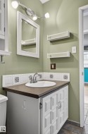 Bathroom vanity featuring a drop-in sink, chrome fixtures, and white paneled cabinetry - 