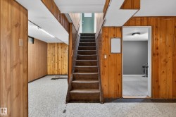 Staircase with carpeted treads and wood-paneled walls - 