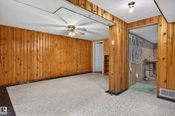 Room featuring wood-paneled walls, a patterned flooring, and a ceiling fan with integrated lighting - 