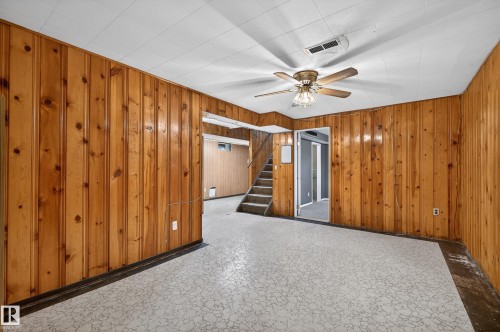 Room featuring wood paneling, a patterned ceiling, and a ceiling fan with light fixture - 13427 114 Street, Edmonton, AB 