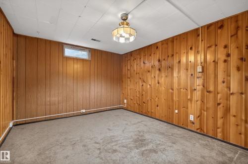 Room featuring wood paneling, drop ceiling, and a flush mount light fixture - 13427 114 Street, Edmonton, AB 