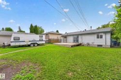 Expansive backyard featuring a large grass area, wood deck, and a sliding glass door entry to the home - 
