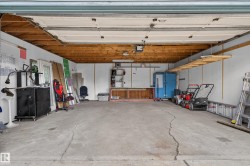 Spacious garage with exposed wood ceiling beams, concrete flooring, and ample storage shelving - 