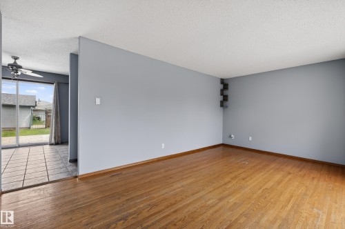 Spacious room with wood-finish flooring, light gray walls, and textured ceiling - 13427 114 Street, Edmonton, AB 