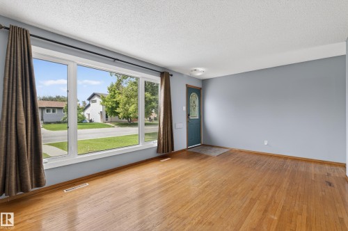 Hardwood flooring and a large picture window define this interior space - 13427 114 Street, Edmonton, AB 
