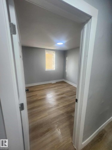 Room featuring wood-finish flooring, light gray walls, a recessed ceiling light, and a window with blinds - 11308 94 Street, Edmonton, AB 