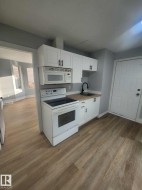 Kitchen featuring white cabinetry, wood-finish countertops, and a black gooseneck faucet - 