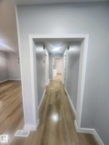 Hallway featuring wood-finish flooring, light grey wall paint, white trim, and recessed lighting - 11308 94 Street, Edmonton, AB 