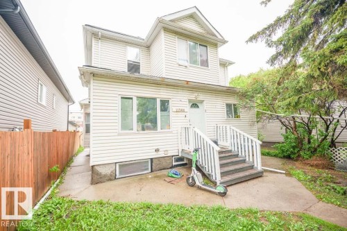 Two-story property featuring white horizontal siding and a prominent front entrance with white railings - 11308 94 Street, Edmonton, AB 
